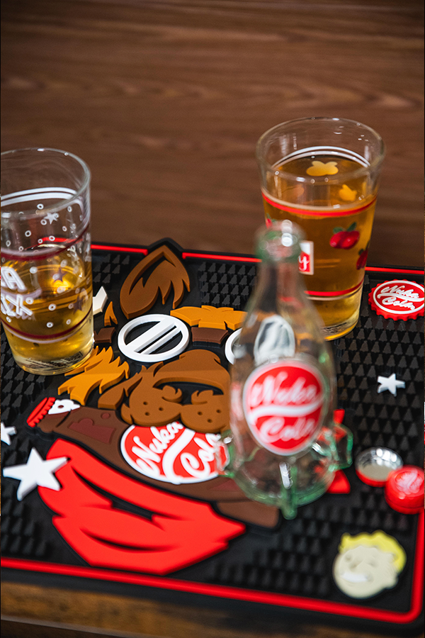 Two glasses of beer and a bottle on a decorative mat with a brand logo.