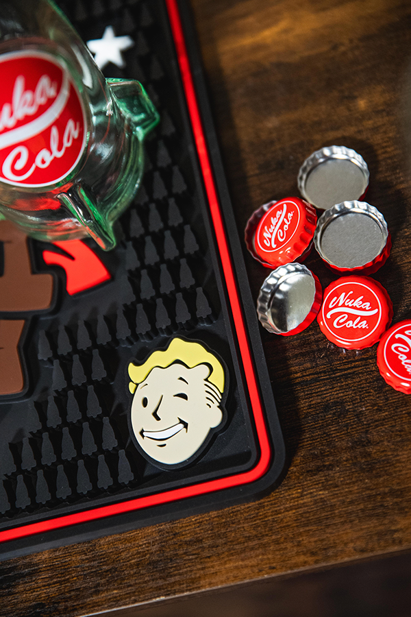 Nuka Cola bottle cap and logo on a black textured mat with a wooden surface.