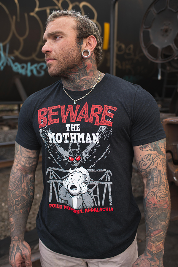 Man wearing a black t-shirt with a graphic design and text, standing in an urban setting.