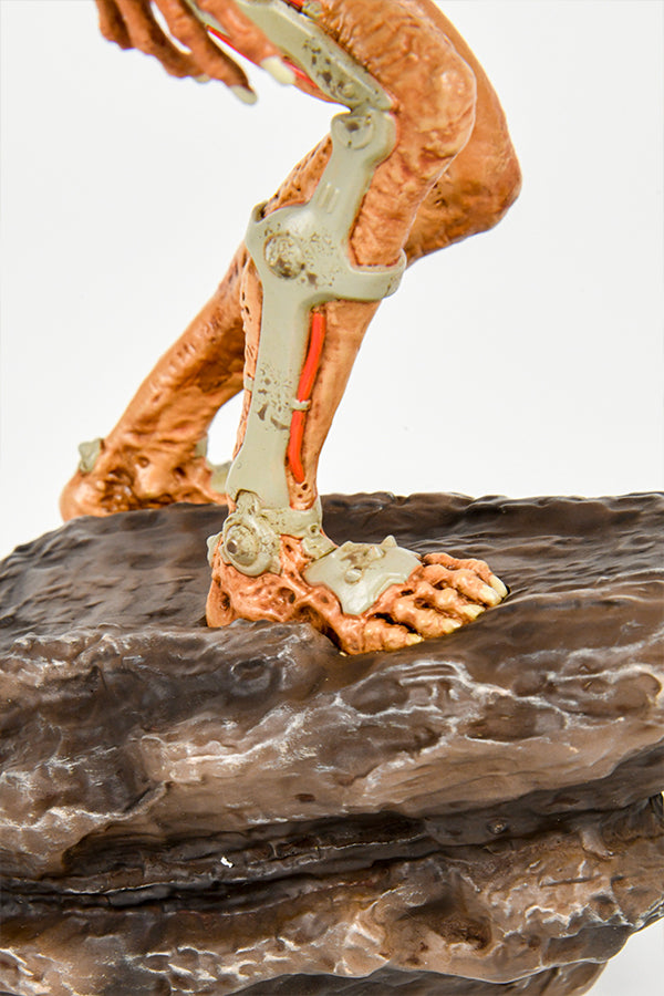 Close-up shot of the DOOM Eternal Revenant Statue, showing the details of the legs and feet with their cybernetic enhancements and rotting flesh, as well as the boulder beneath them.