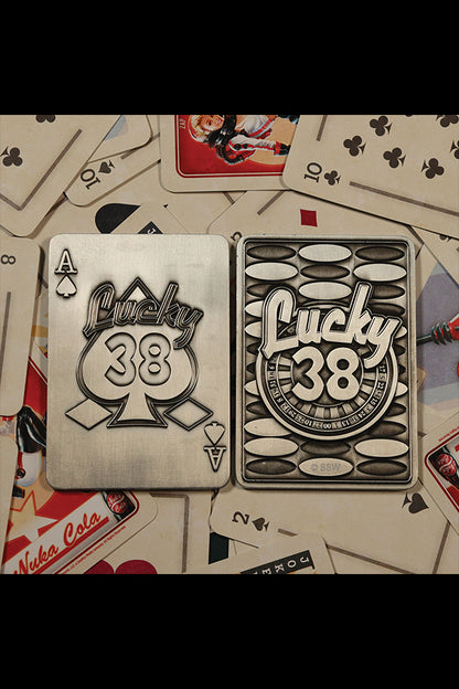 Top-down shot of the back of the Lucky 38 metal Ace of Spades, with the metal poker chip and metal pin badge among playing cards and chips.
