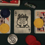 Top-down shot of the back of the Lucky 38 metal Ace of Spades, with the metal poker chip and metal pin badge among playing cards and chips.
